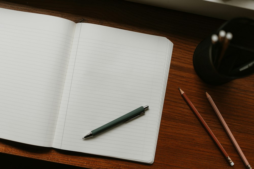 Cuaderno abierto con lápices sobre madera